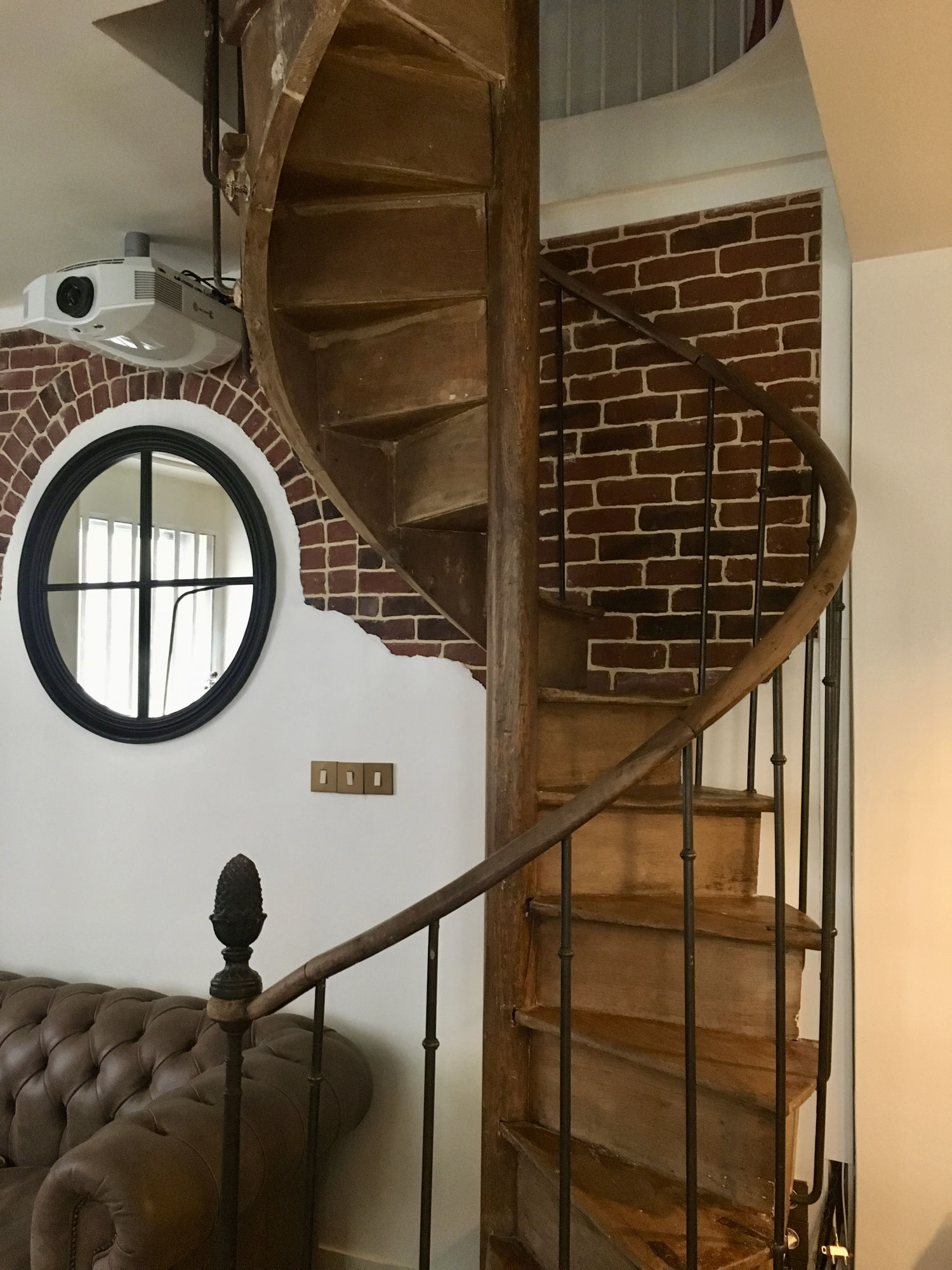 Bespoke feature wall with exposed brick arch, plaster contour, and round antique-style mirror